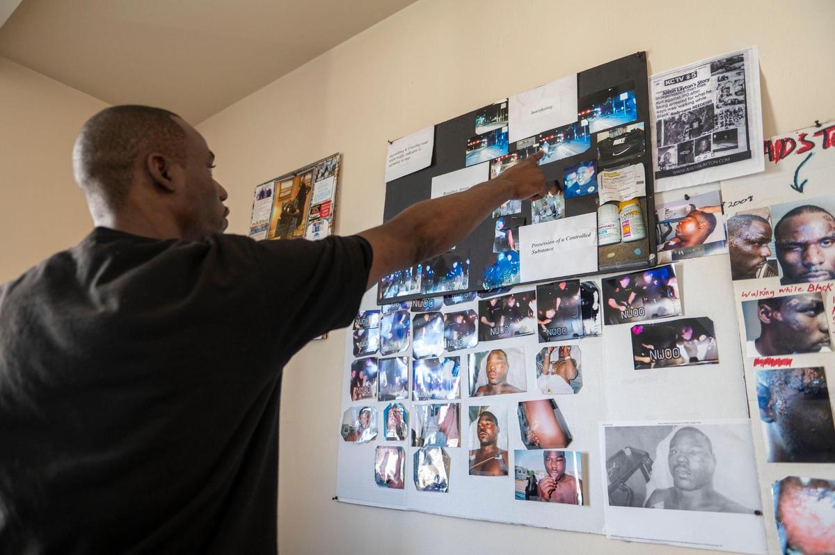 Justin Layton points to photos he displays on a wall of his experience with the Independence police department at his home in Kansas City on Tuesday, March 15, 2022. Layton claims the police violated his civil rights when they arrested for “jaywalking” just over two years ago.