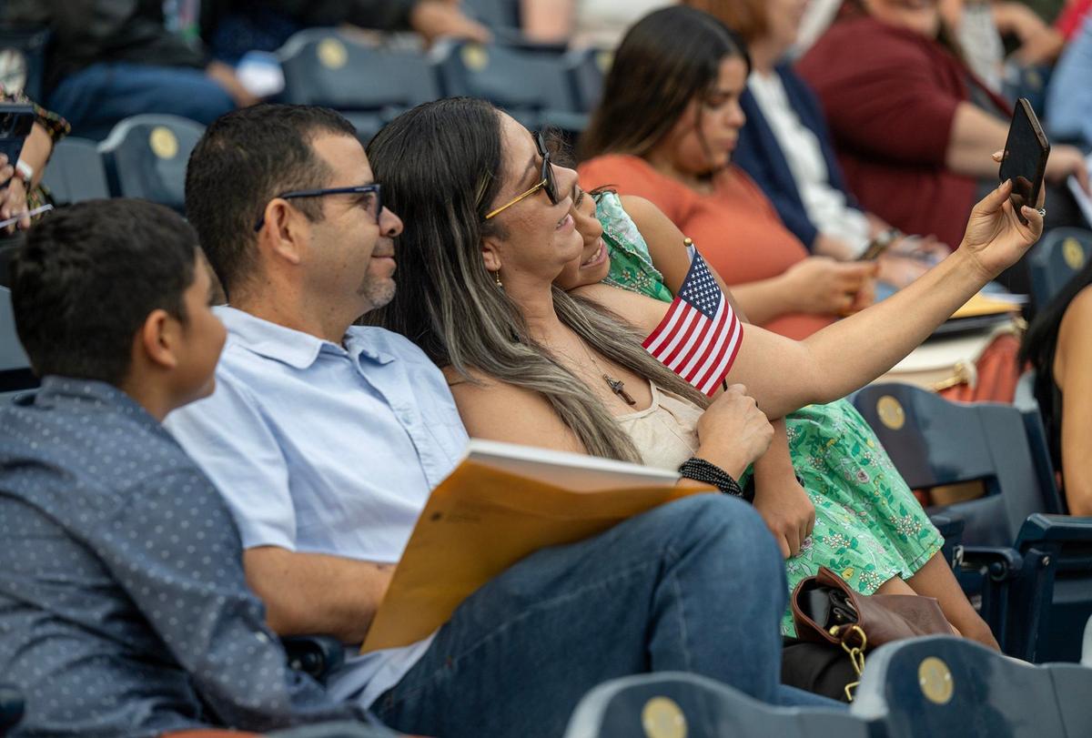 Lorena Alvarez Meza, a native of Jalisco, Mexico, takes a selfie Thursday with her family including daughter, Eliza Franco, 8, her husband, Carlos Franco, and son Iker Franco, 10, as during the naturalization ceremony at Kauffman Stadium where she would become a U.S. citizen.