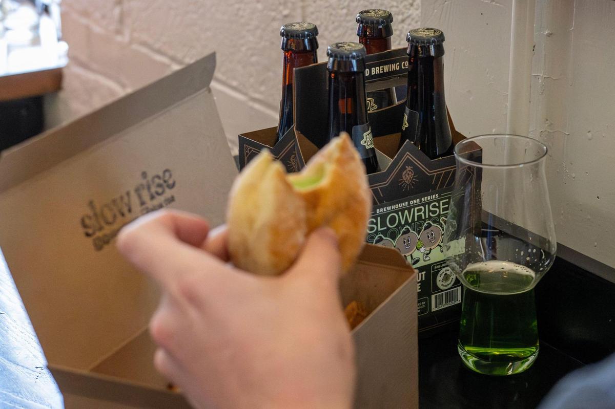 A four-pack of Pandan Coconut Doughnut Ale is seen as a guest enjoys a Pandan Coconut doughnut during the release party at Boulevard Brewing Tours and Recreation Center on Sunday, March 9, 2025, in Kansas City.