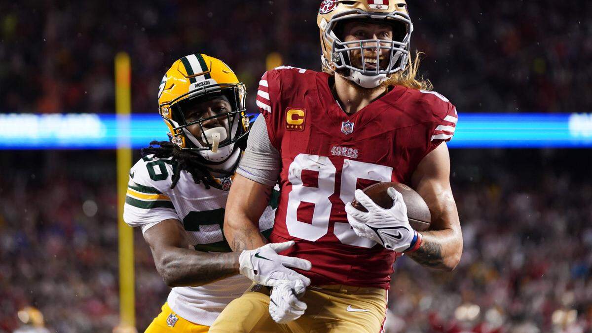 San Francisco 49ers tight end George Kittle (85) scores a touchdown against Green Bay Packers safety Darnell Savage (26) during the second quarter in a 2024 NFC divisional round game at Levi’s Stadium.