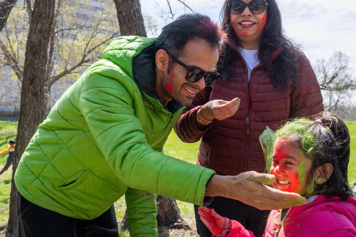 Swapnil Salvi rubs Holi colors on a young girl at a Holi Festival of Colors in Overland Park on Sunday.