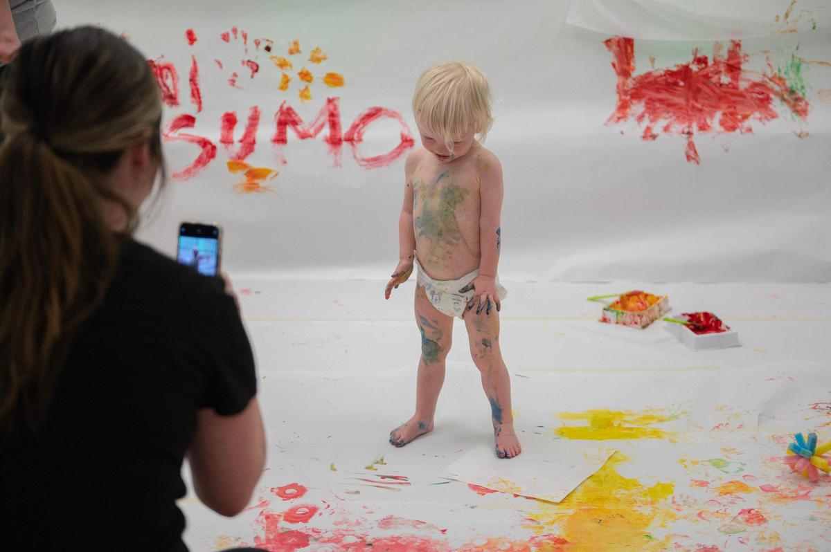 One-year-old Lucy Hoelting strikes a pose for a photo after participating in the artistic process at the baby paint crawl.