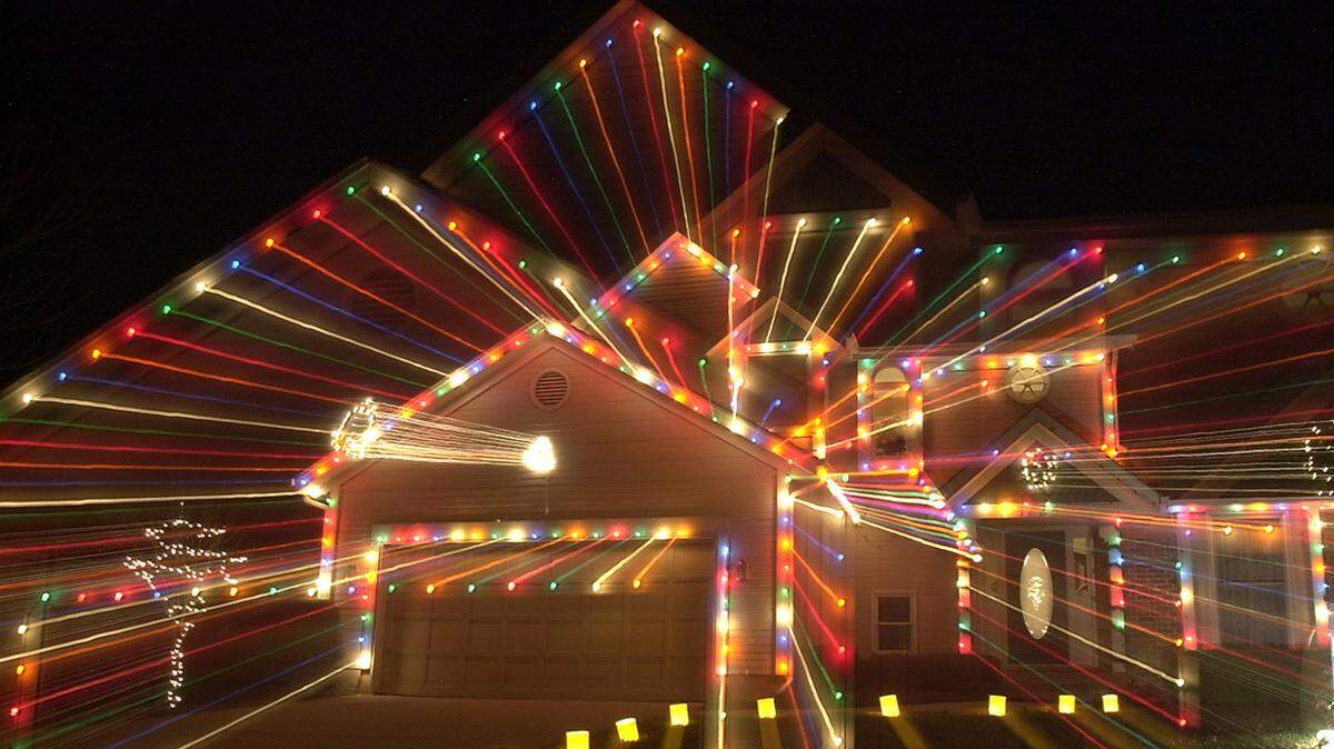 Residents in a south Olathe neighborhood have been decorating their homes and yards with holiday lights and giant greeting cards for the last 16 years. ‘Christmas Card Lane’ brings an average of 11,000 car-bound visitors each holiday season. Colorful lights on a house along Sleepy Hollow illuminate the night sky.  (Whitney Curtis/The Kansas City Star)     NOT PUBLISHED ORG XMIT: 7A101VIS