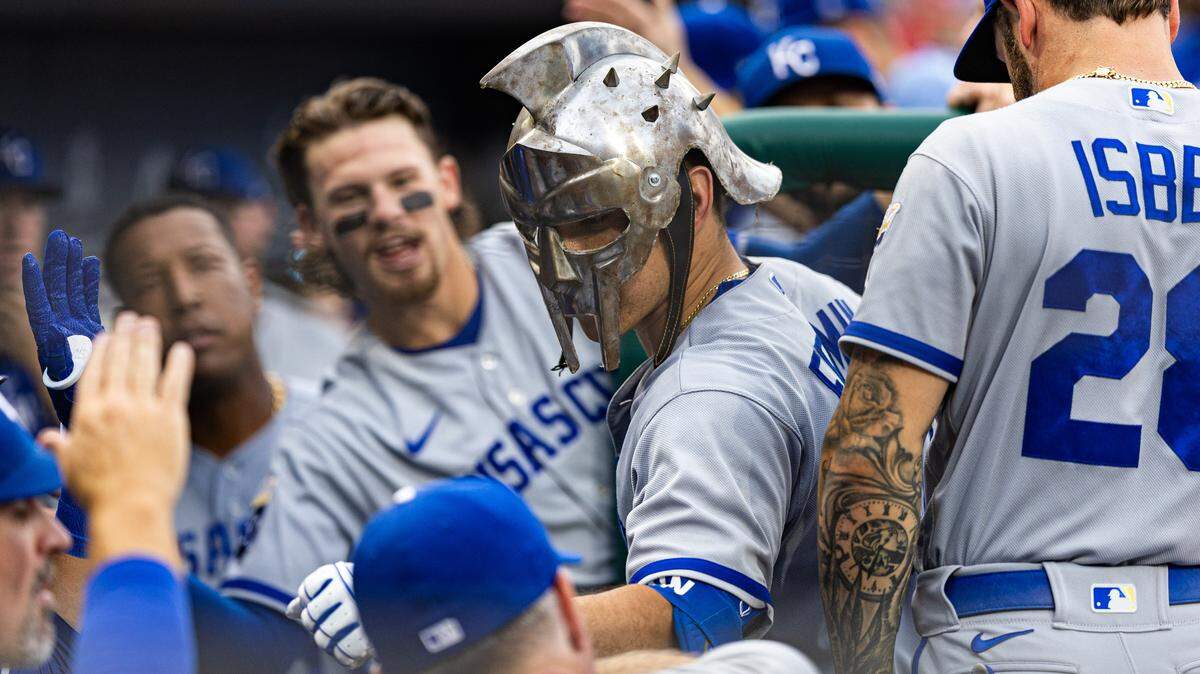 Kansas City Royals catcher Freddy Fermin (34) wears a gladiator helmet while being congratulated in the dugout after hitting a home run against the Philadelphia Phillies at Citizens Bank Park on Aug. 5, 2023.