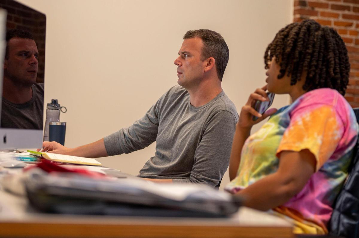 COO Greg Moore, left, and Social media manager Laken Horton of Charlie Hustle have a brief meeting at Charlie Hustle headquarters.