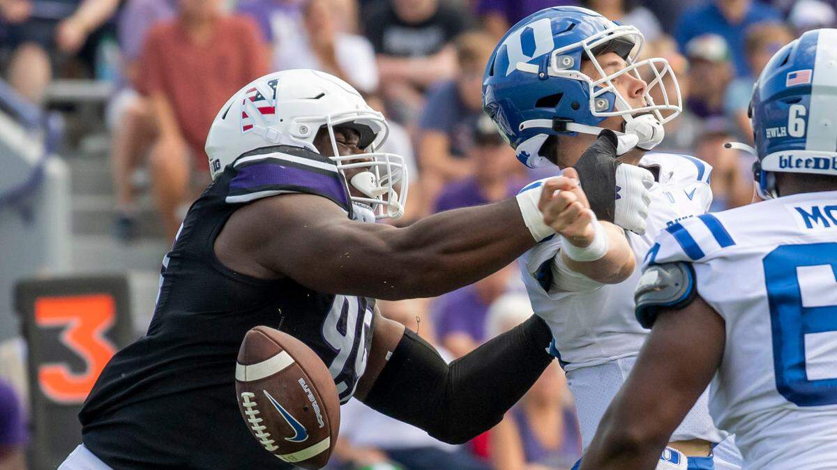 Northwestern defensive lineman Adetomiwa Adebawore, left, forces a fumble on Duke Blue Devils quarterback Riley Leonard during a game last season.