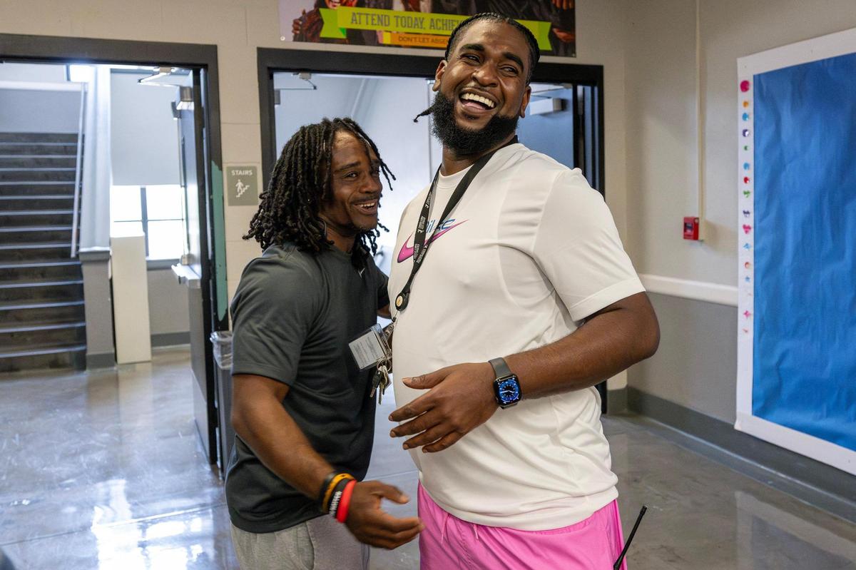 Warren Bennett II, a P.E. teacher at Northeast Middle School, embraces Vincent Gunnels while speaking in a hallway on Monday, June 16, 2025, in Kansas City.