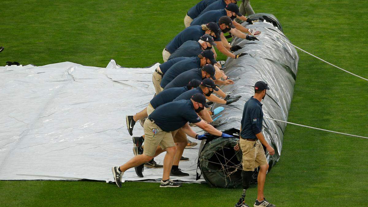 Minnesota Twins grounds-crew members roll out a tarp for expected rain which has delayed the start of a baseball game with the Kansas City Royals on Friday, Aug. 14, 2020, in Minneapolis. (AP Photo/Bruce Kluckhohn)