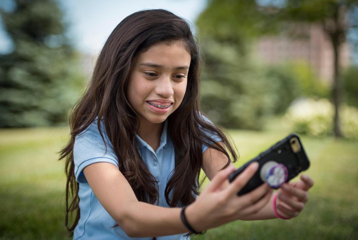 Moments after receiving her new braces, Yuliana Alvarado, 11, happily takes a selfie outside Burleson Orthodontics in Kansas City.