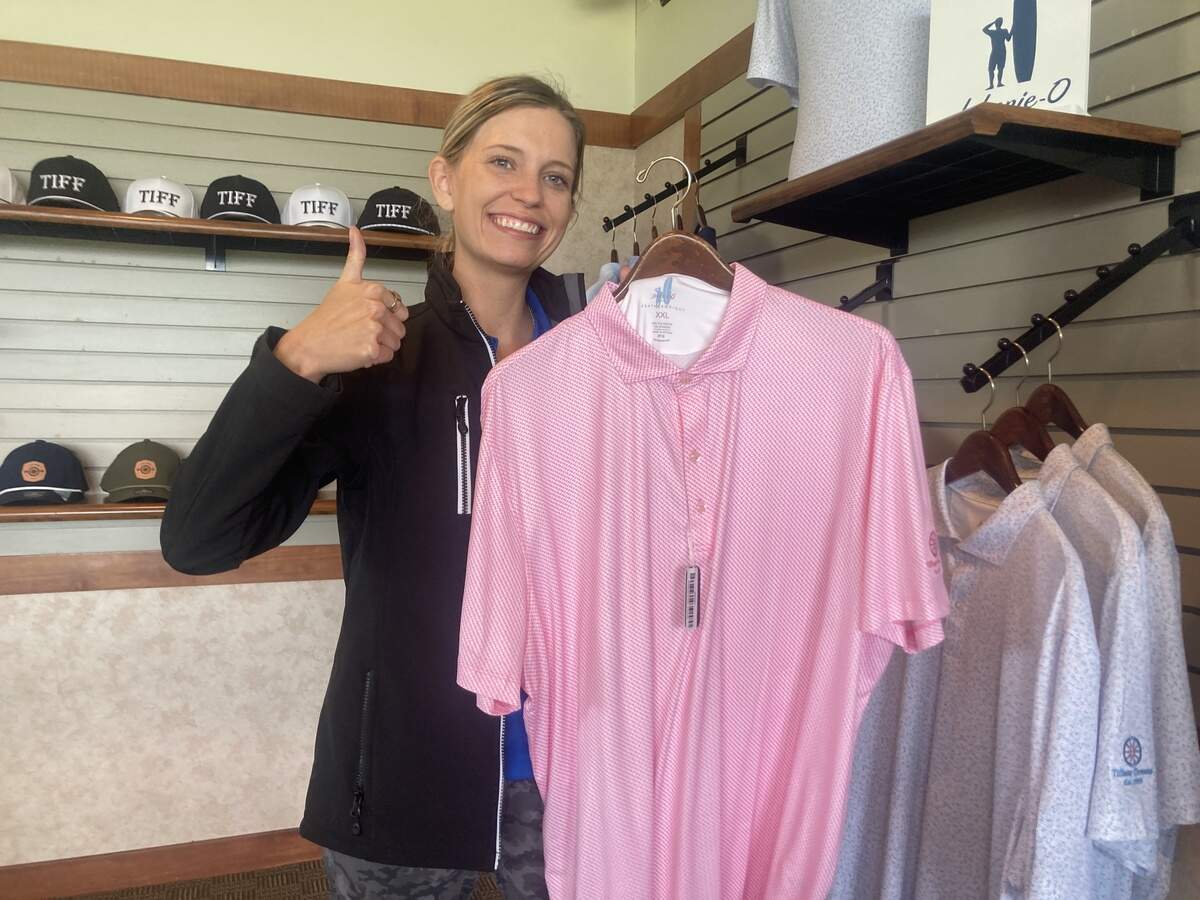 Tiffany Greens Golf Club General Manager Hannah Noll holds up the Johnnie-O shirt bought by a player on the Dutch World Cup soccer team.