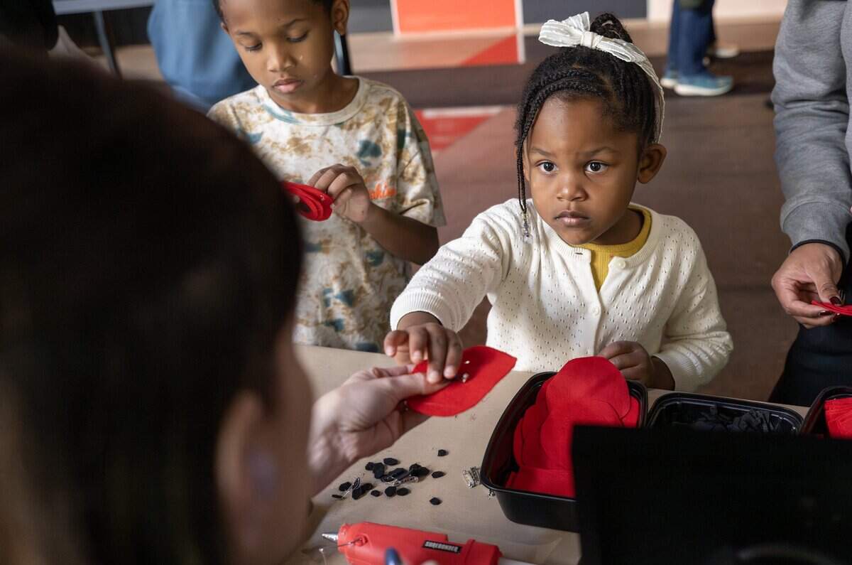 Kristin Keckler-Alexander, volunteer program manager, left, gives 4-year-old Emma Moss a felt poppy pin after gluing the clasp on the back in honor of Veterans Day at the National WWI Museum and Memorial on Tuesday, Nov. 11, 2025.