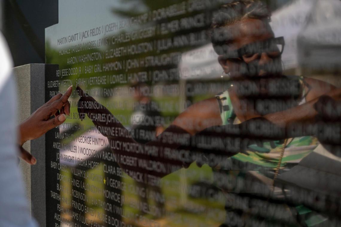 Andrea Robins directs her attention to one of her ancestors that is on The Liberty African American Memorial at Fairview and New Hope Cemetery in Liberty on Saturday, June 18, 2022.