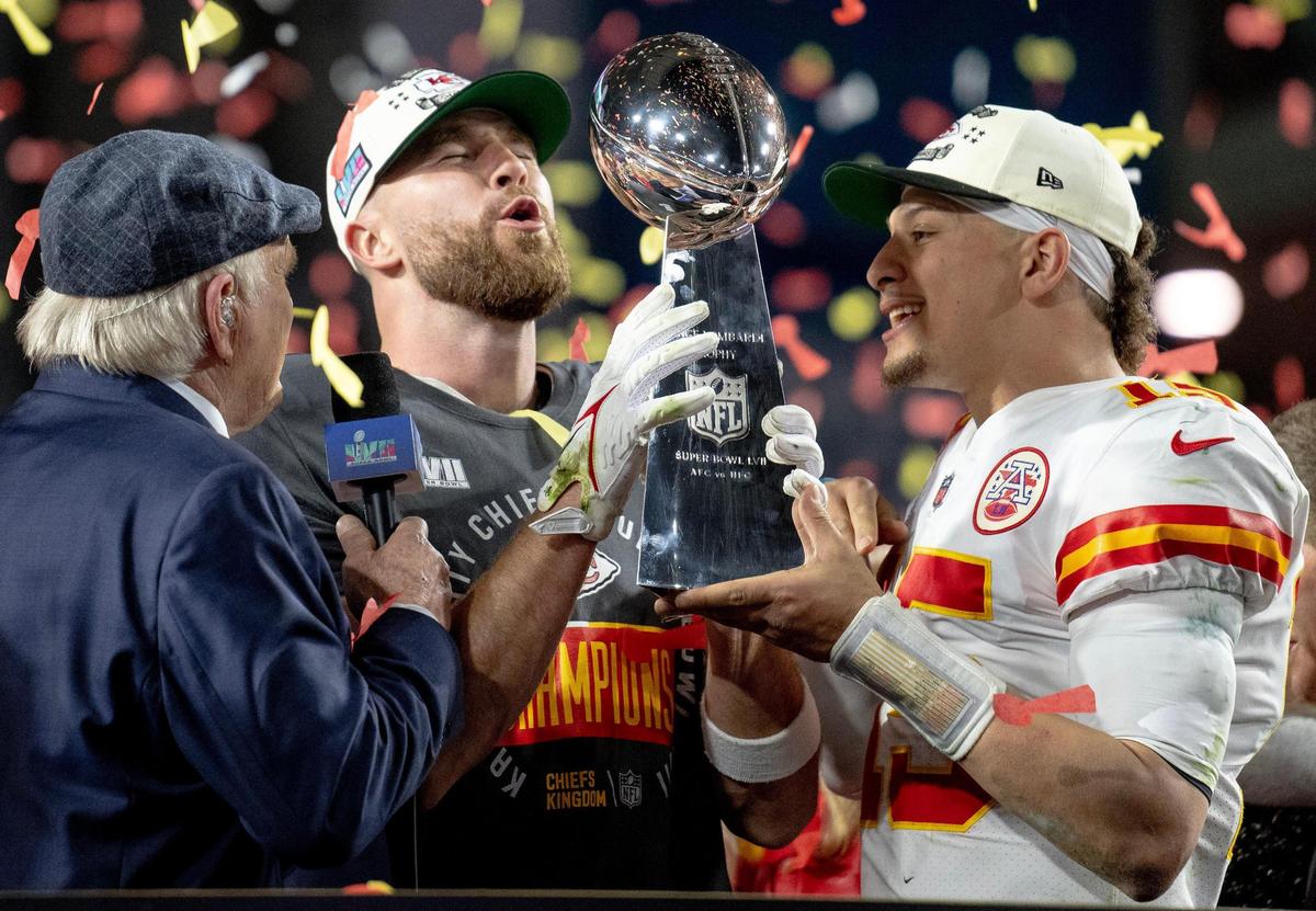 Kansas City Chiefs quarterback Patrick Mahomes, right, hands the Vince Lombardi Trophy to tight end Travis Kelce after defeating the Philadelphia Eagles 38-35 in the Super Bowl LVII football game on Sunday, Feb. 12, 2023, in Glendale, Ariz.