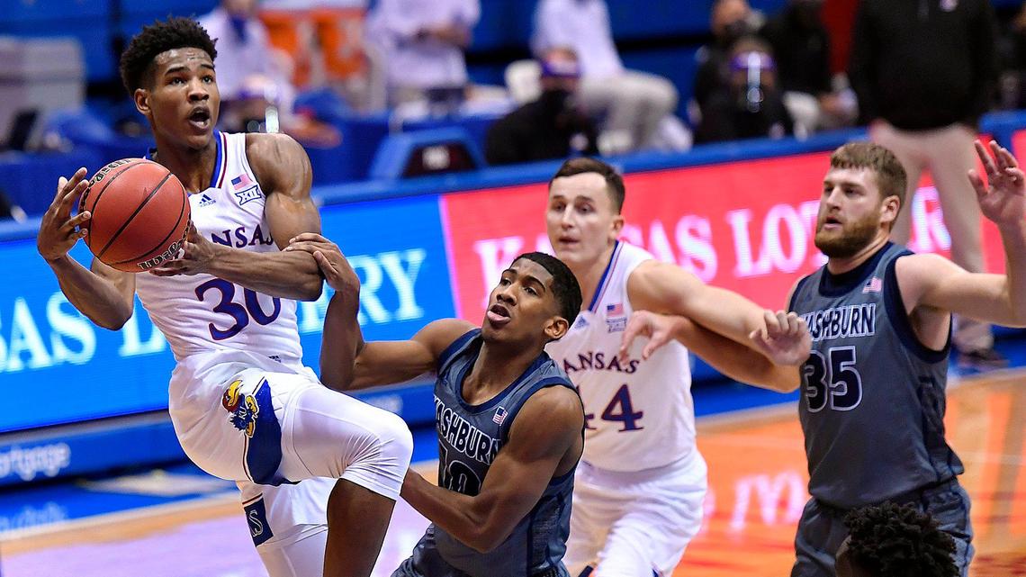 KU’s Ochai Agbaji (left) is fouled by Washburn’s Connor Deffebraugh as he drives to the basket during the first half of Thursday night’s game at Allen Fieldhouse (Dec. 3, 2020)