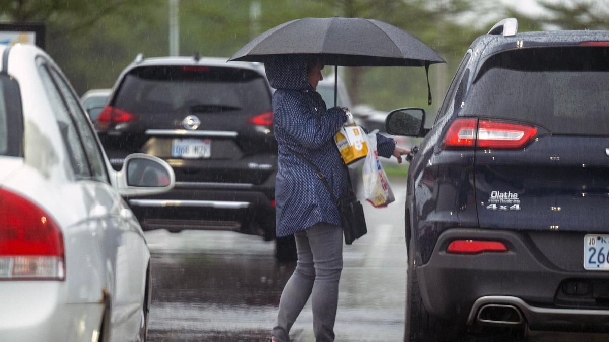 An umbrella shields a shopper from heavy rain as the first of a series of storms moved through Shawnee on Thursday, April 25, 2024. The National Weather Service is expecting storms to pass through the Kansas City region for the next couple of days.