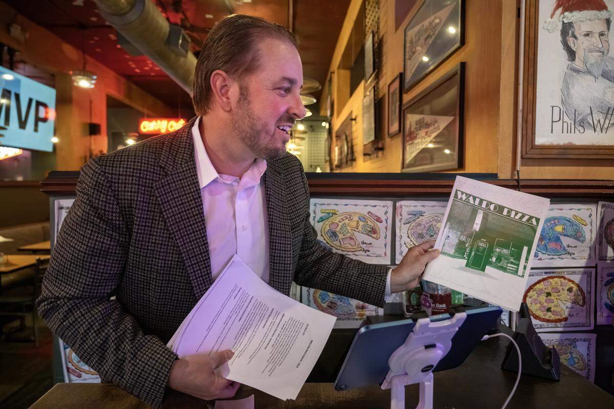 Whitney VinZant, left, chief executive officer of W. VinZant Restaurants, shows a new graphic of Waldo Pizza, one of the restaurants in his restaurant group.