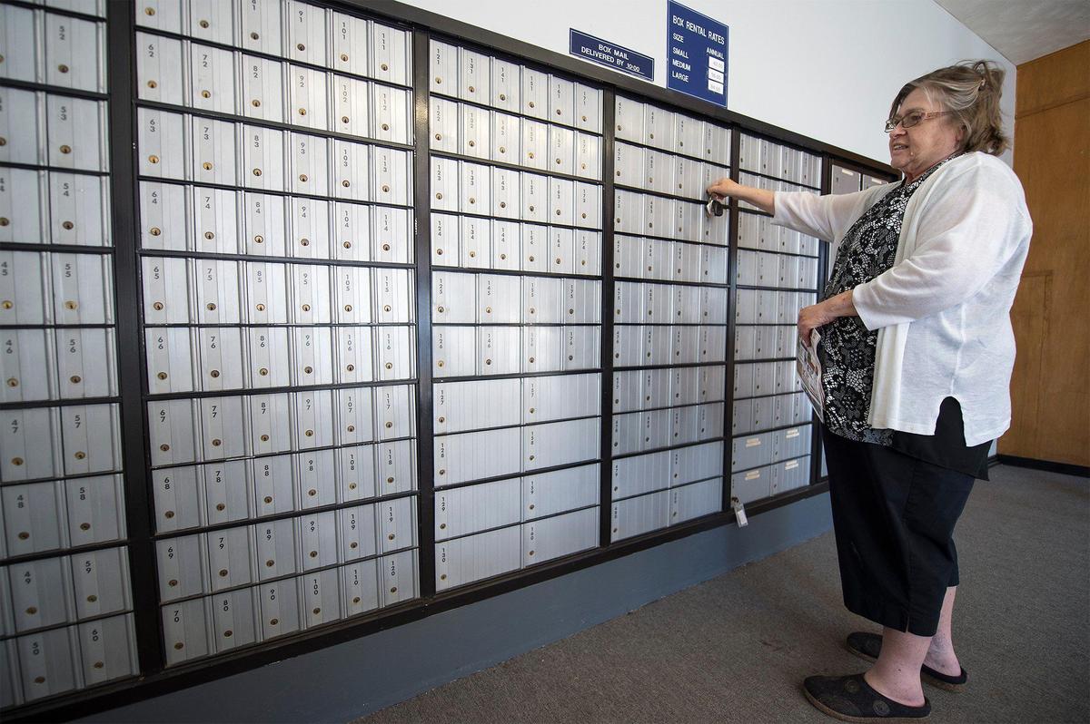 Phyllis Sprenkle, a retired school administrator who lives in tiny Sheldon, Missouri, picks up her mail Wednesday from her P.O. box at the post office in Sheldon. “We have had to fight for it (the post office),” Sprenkle said. “It has cut down hours, which makes it more inconvenient, but it’s here.”