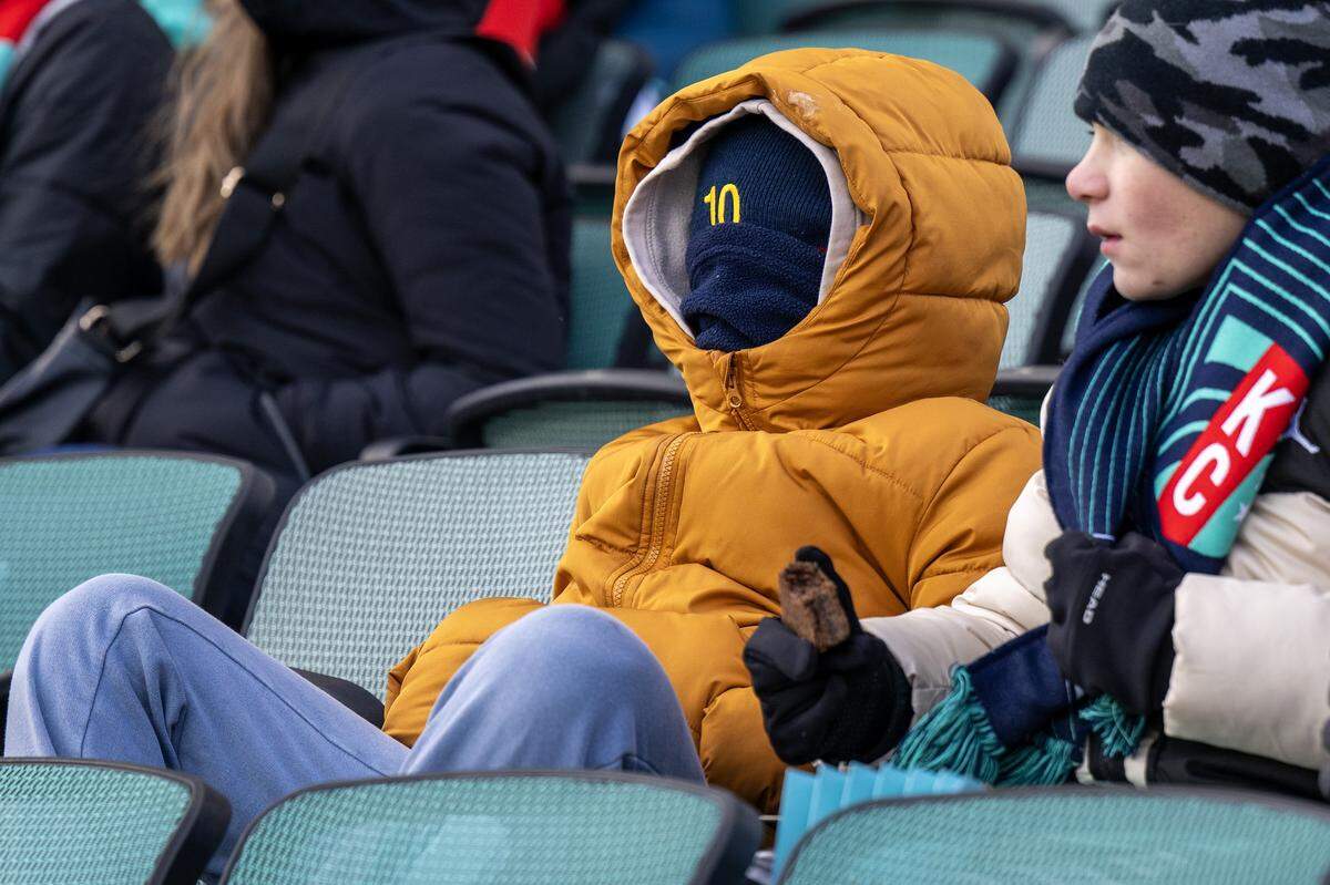 A heavily bundled fan takes in the action during the KC Current-Gotham NWSL quarterfinal playoff match at CPKC Stadium in Kansas City on Sunday, Nov. 9, 2025.