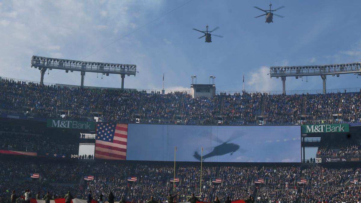A military helicopter fly over was conducts as an American flag was unfurled during the playing of the national anthem before the start of the game between the Baltimore Ravens and the Cleveland Browns at M&T Bank Stadium.