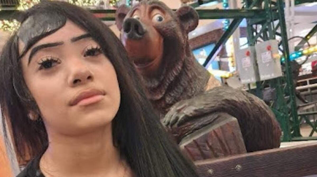 A picture of a person standing in front of a bear statue.