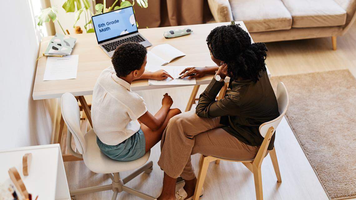 High angle portrait of young African American girl working with tutor at home school education learn tutoring help assistance