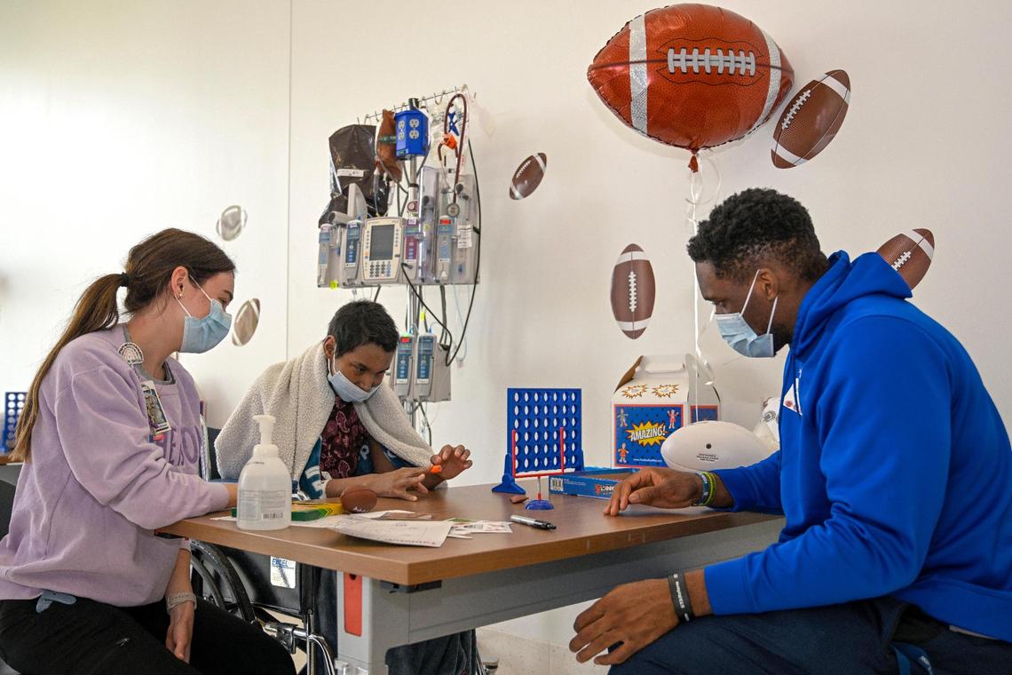 Kim White, left, a Child Life Specialist, looks on as Carlie Foutch, 15, played a football game with NFL Draft prospect Ikenna Enechukwu, formerly of Rice University, who was one of several football players who paid a visit to patients on Wednesday, April 26, 2023, at by Children’s Mercy Research Institute in Kansas City.