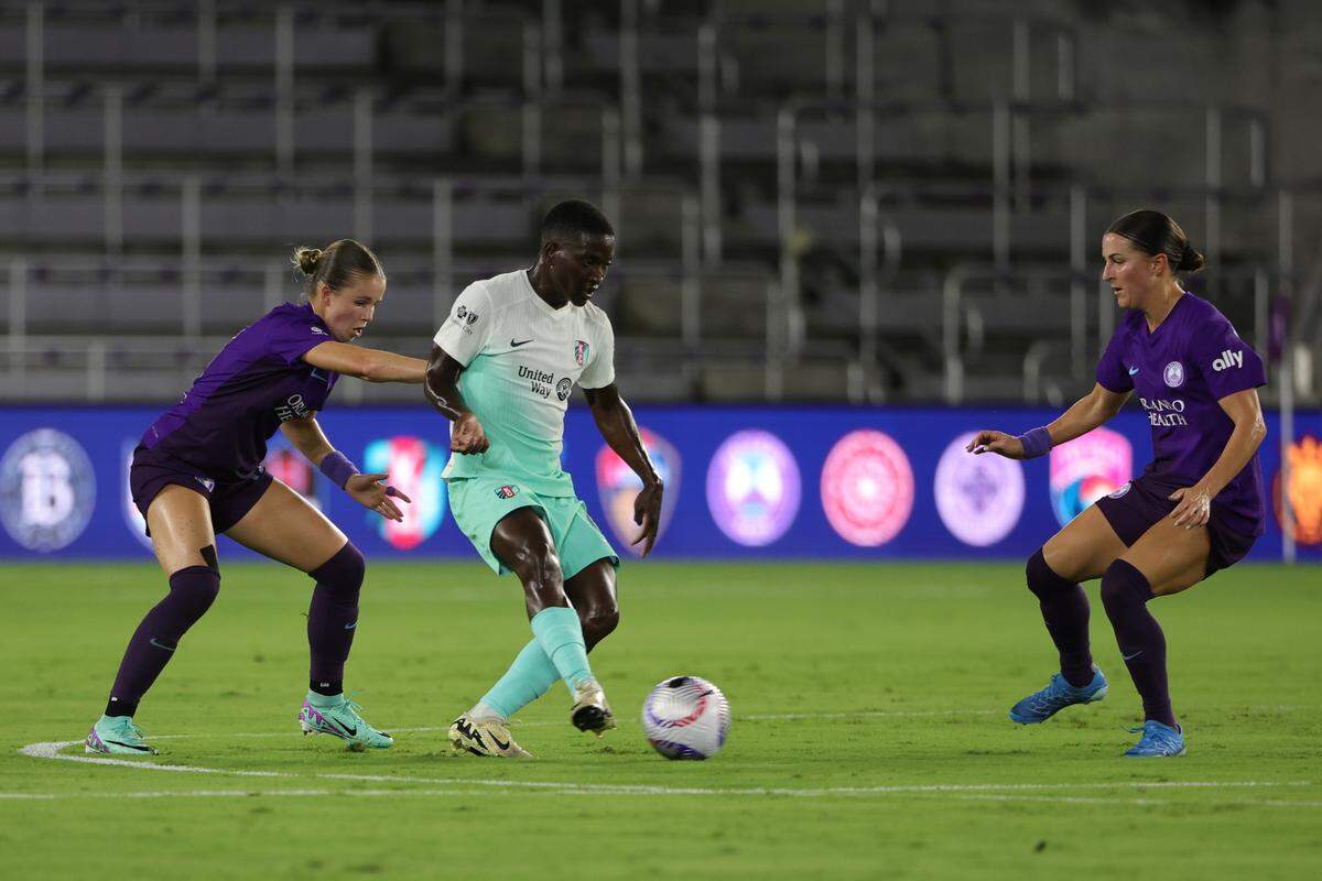 Kansas City Current forward Temwa Chawinga, center, controls the ball as Orlando Pride midfielder Haley McCutcheon, at left, defends on Friday evening at Inter&Co Stadium.