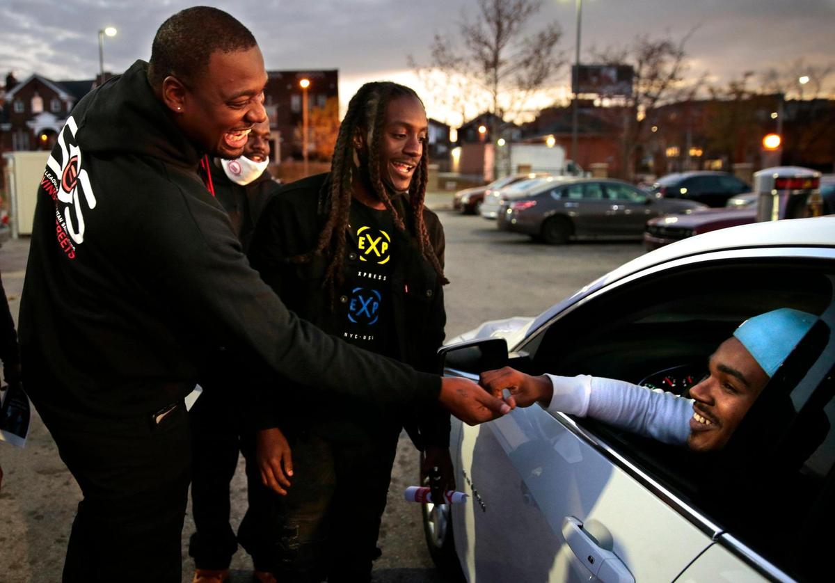 The Urban League’s Saving our Streets team members Dsmoovee Shabazz, left, and Eric Harris greet rapper Taylor Merriweather (Lil Tay) as they hand out fliers on a gas station parking lot in the Kingsway East neighborhood promoting the group’s gun violence de-escalation efforts on Monday, Nov. 9, 2020. Lil Tay founded the trio 3 Problems while in high school and the group soared in popularity. Since then, James Johnson, Jr. (Swagg Huncho) was found shot to death and Terrell Brown, Jr. (Relly Rell) is serving a ten year sentence for second degree murder.