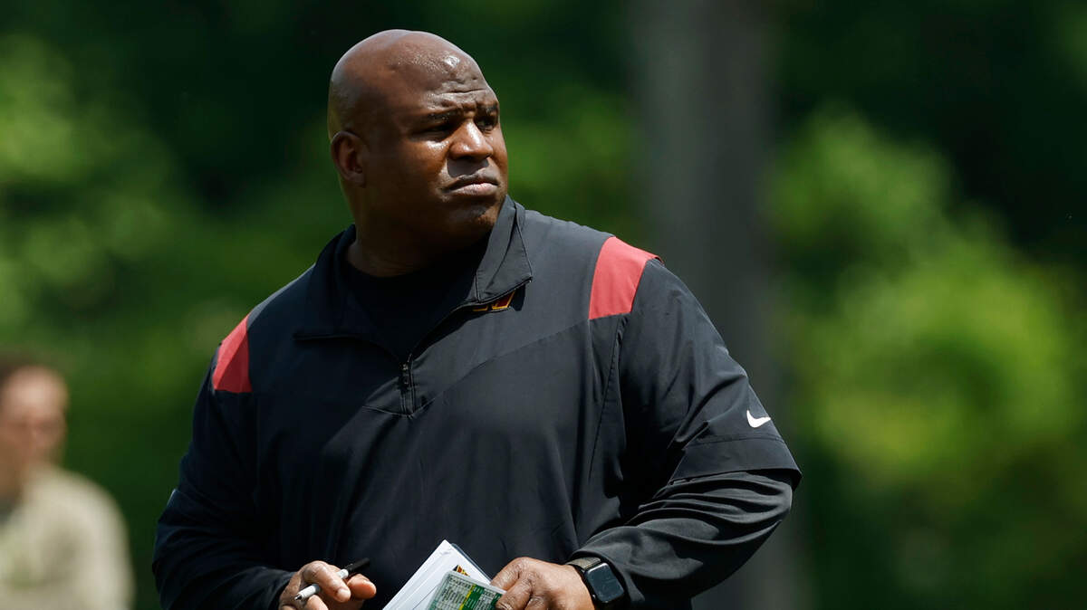 Washington Commanders assistant head coach/offensive coordinator Eric Bieniemy stands on the field during Commanders rookie minicamp at Commanders Park.