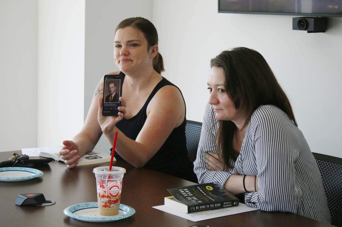 Marlo Silva of Spring Hill shares a photo of the Golden State Killer with Blair Johnson of Olathe and the rest of the attendees at the Crime and Cookies book club at Olathe’s Downtown Library.