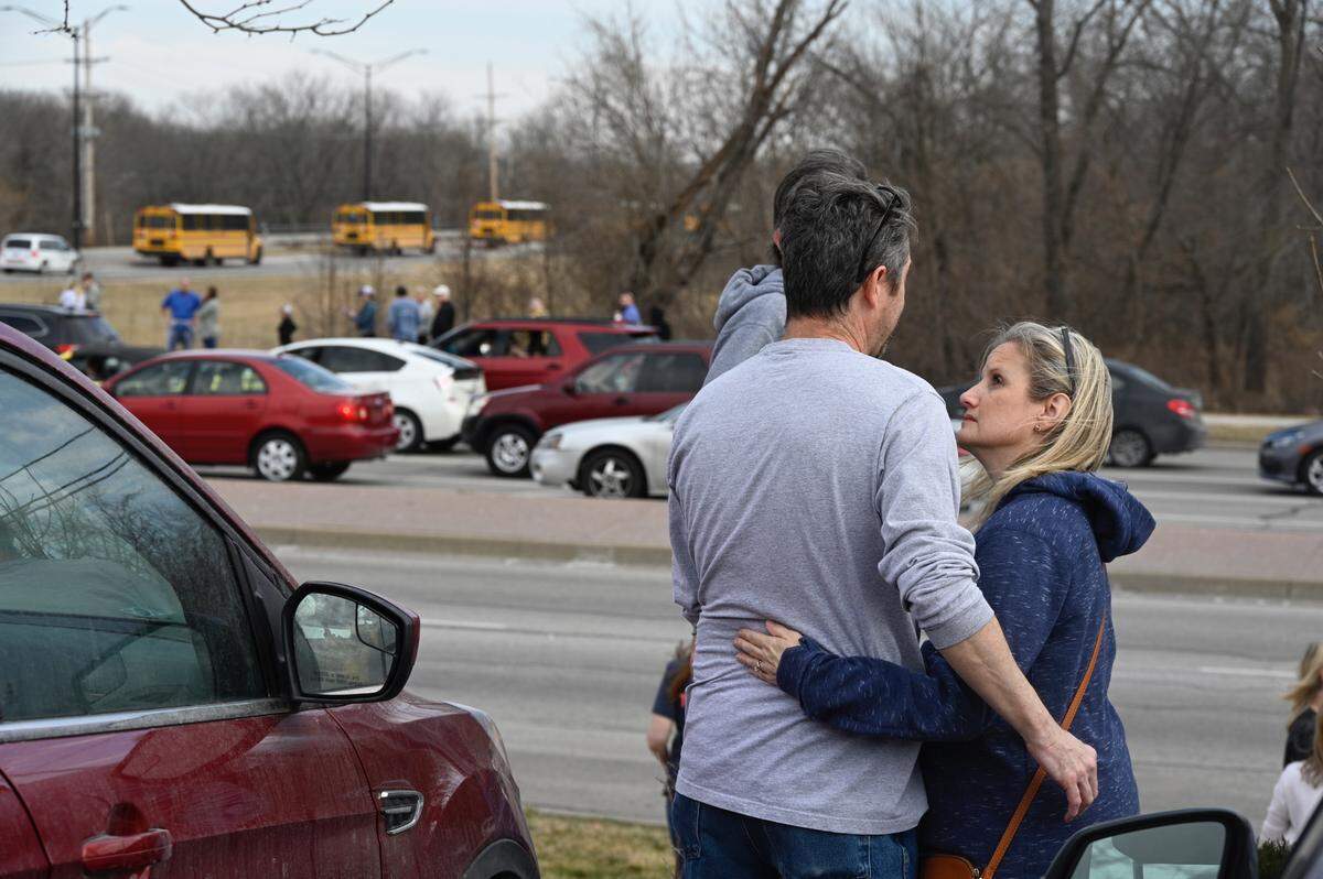 Holly and Eric Thompson wait for their Olathe East High School freshman to be evacuated from the school Friday after a shooting at the school. “It finally came here, heard about it forever and ever, but now it’s here,Ó Eric Thompson said.