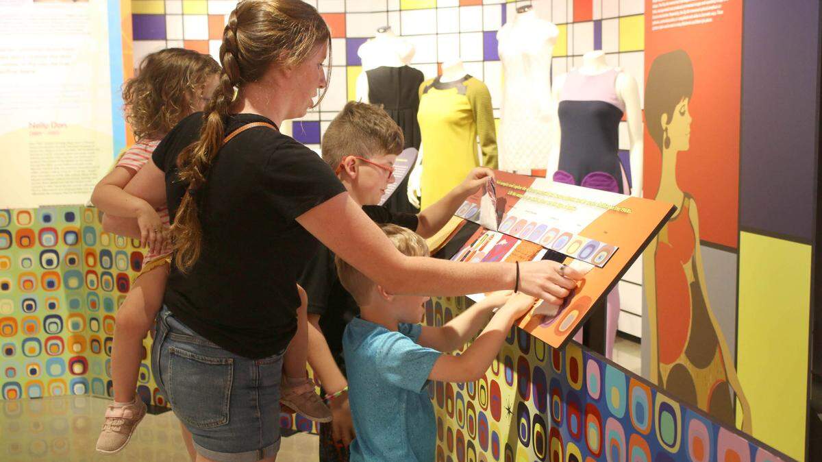 Casie Lacey of Osawatomie and her kids, Anna, Adam and Aden, get a feel for ’60s fabrics at a 2024 fashion exhibit at the Johnson County Museum. The museum is hosting a free admission day Saturday, Sept. 13, which includes special exhibits.