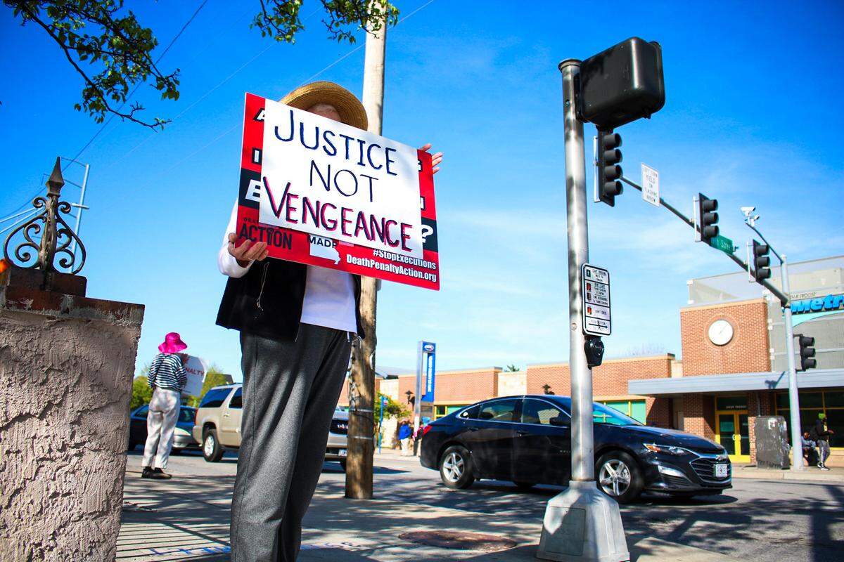 A protester holds a sign that reads “Jutice not vengence” as members of Missourians to Abolish the Death Penalty gather at the corner of 39th Street and Troost Avenue April 9, 2024 ahead of the state’s execution of Brian Dorsey.