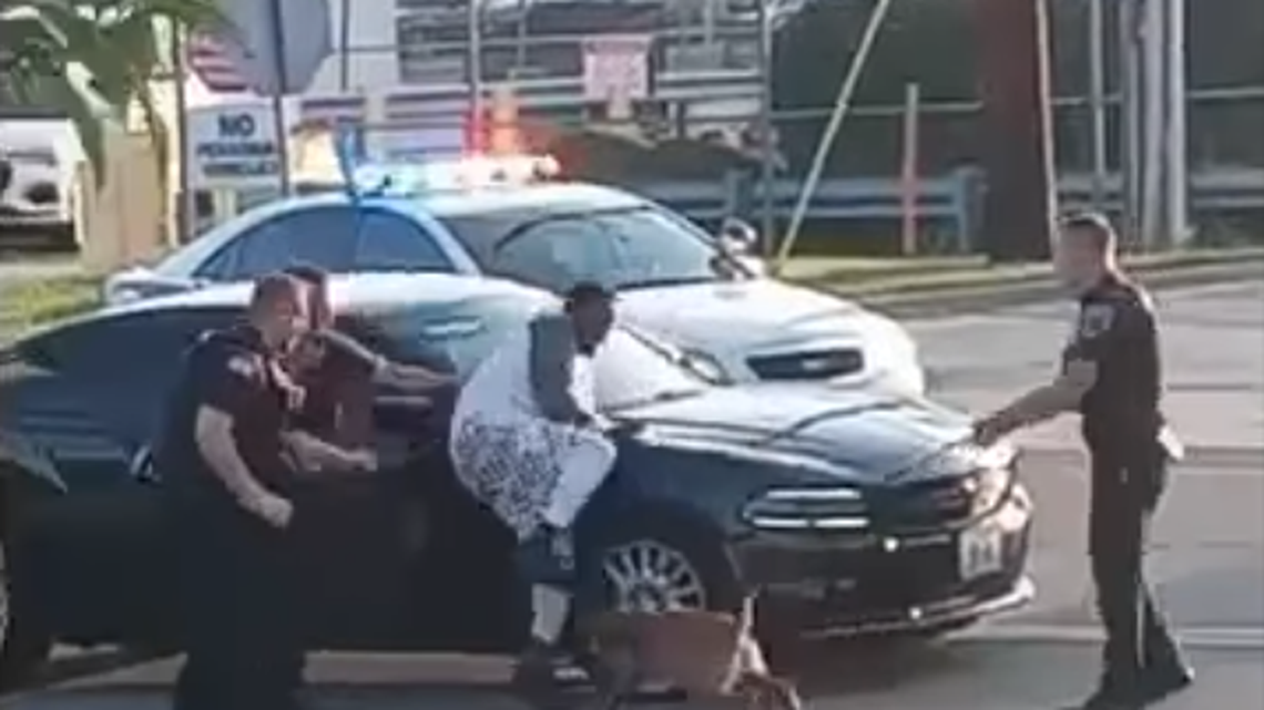 A video of an arrest in Woodson Terrace, Missouri, shows officers hold a man over a car hood then release a police dog on him. Screengrab from Latonya Jackson Whittier on Facebook.