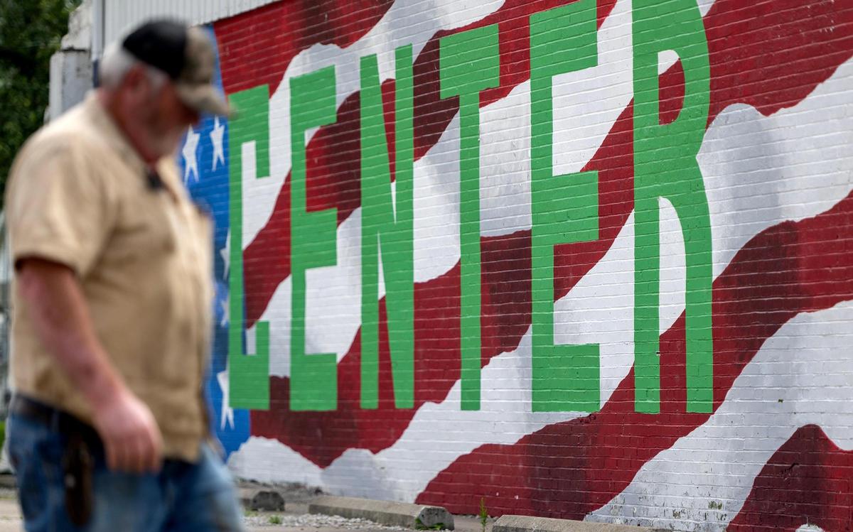 A person walks past an American flag mural painted on the side of the City Hall building in Center, Mo.