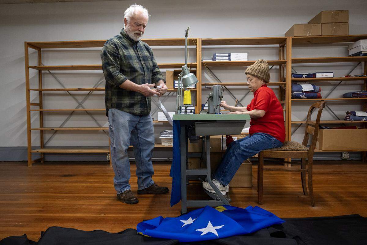 At All Nations Flag Co., custom order manager Randy Carney looks over the banding for a Curaçao flag as he works with Phuong-Thu Nguyen, 78, who was sewing the fabric together to make the flag on Thursday, Jan. 8, 2025, in Kansas City. Curaçao is one of the nations participating in the FIFA World Cup matches in Kansas City this summer.