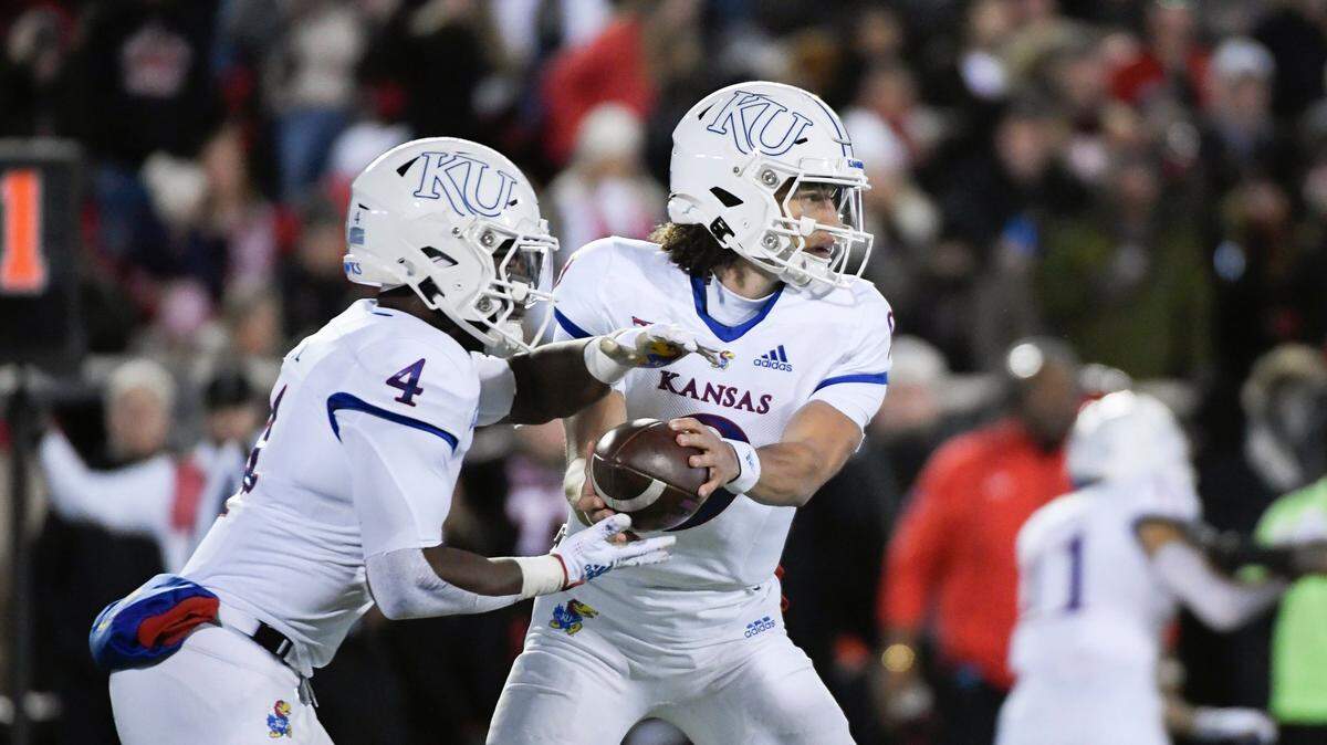 Kansas quarterback Jason Bean (right( hands off to running back Devin Neal during the first half against Texas Tech on Saturday, Nov. 12, 2022, in Lubbock, Texas.