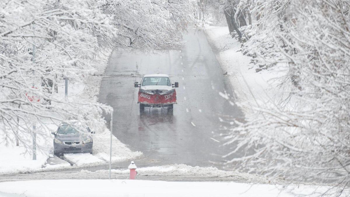 A snow plow makes its way along Gillham Road as heavy snow falls on Tuesday in Kansas City.