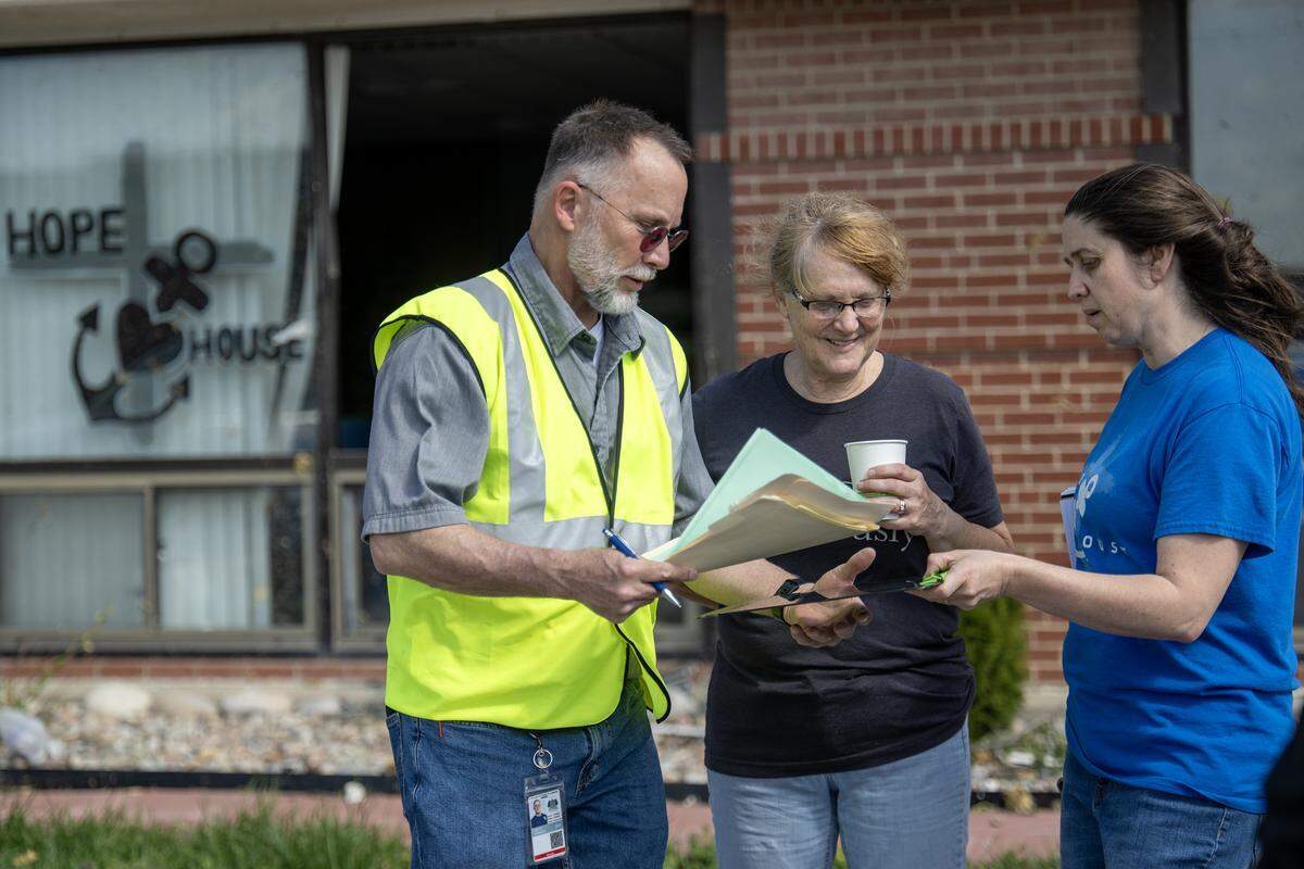 Keith Hodges with the City of Ottawa, talks with Michelle Graf, center, and Tiffany Wyatt, both of Hope House, a not-for profit food pantry, on Tuesday, April 14, 2026, one day after a tornado hit and damaged the organization in Ottawa, Kansas.