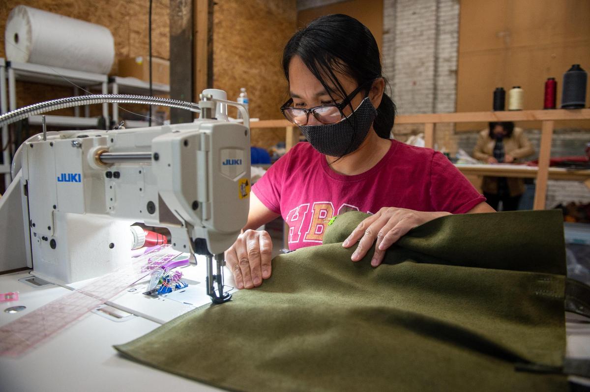 Khaw Naw, a refugee from Burma, stitches a green leather handbag in the Madison Stitch studio in the Crossroads on Wednesday, Nov. 11, 2020. Naw first arrived in the United States in Tulsa, Oklahoma. She moved to Kansas City three years ago. She was working at a US Farathane factory in Riverside, MO when then pandemic hit. John Pryor, the owner of Madison Flitch, first hired Naw to sew masks during the early weeks of the pandemic. Now she’s hired as a full-time to design and stitch handbags for Madison Stitch.