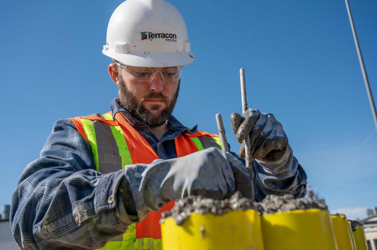 Jordan Orr, of Terracon Consultants Inc., mixes concrete into cylinders as part of the levee project at an Armourdale construction site.