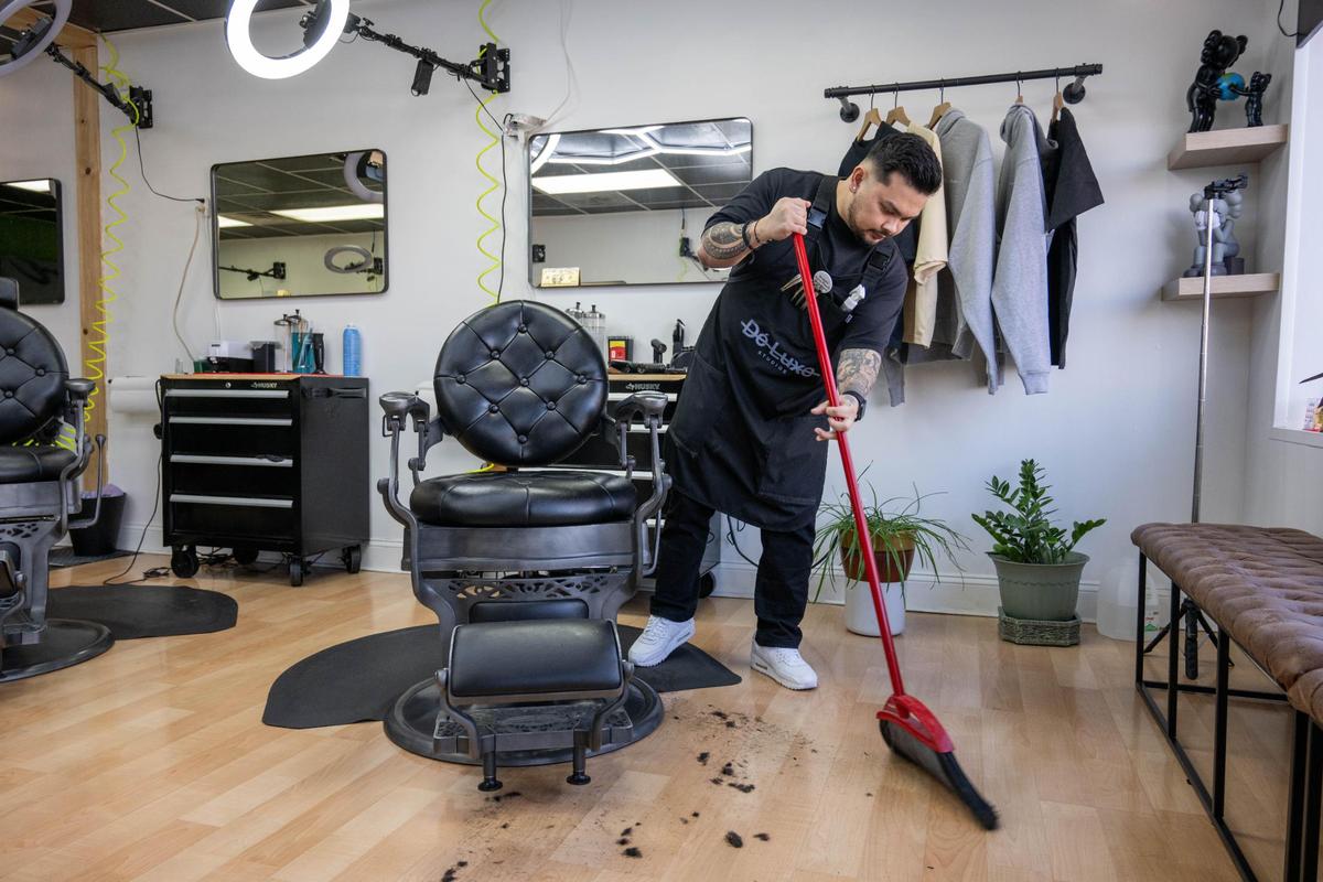 Josh Pacubas sweeps hair at his barbershop Dé Luxe Studios in Mission. “I don’t forget where I came from so we do cuts for the homeless and a lot of the guys here volunteer their services all the time to give back to the community.”