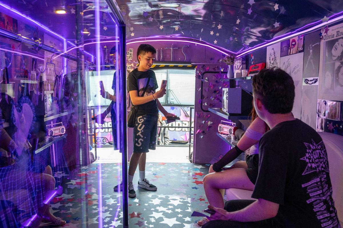 Gustavo Renteria takes a photo of his friends while visiting an interactive exhibit on a bus for Olivia Rodrigo’s Guts World Tour concert.