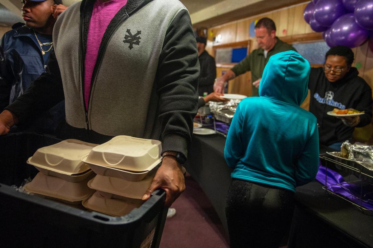 Volunteers gather boxes of prepared meals to deliver to people in need the night before Thanksgiving at the Community Harvest Dinner at 24 Hour Faith Training Center, 2605 Prospect Ave.