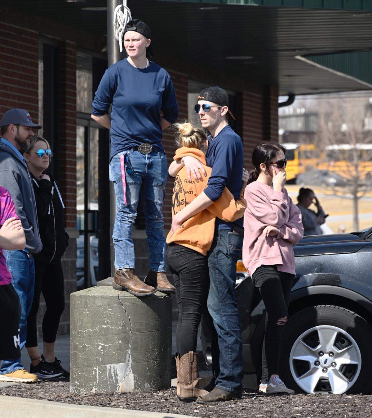 Joe Kathrens hugs Morgan Montgomery, Skyler Pattullo, on light post, wait at the reunification site near 127th and South Black Bob Friday after a school shooting at Olathe East High School. All three live nearby, have friends at the school.