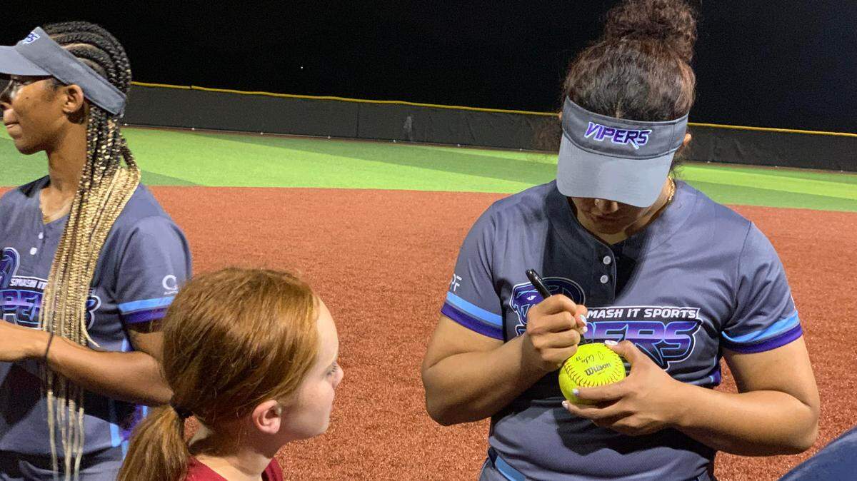 Jocelyn Alo signs a ball for 9-year-old fan Journi Hill. Alo made her professional softball debut Friday in Shawnee for the Women’s Professional FastPitch league.