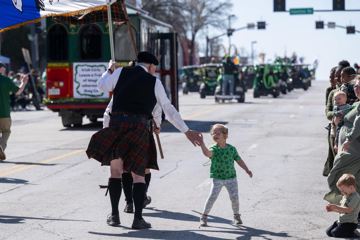 A young bystander slaps five with a parade walker during the Kansas City St. Patrick’s Day Parade on Monday, March 17, 2025.