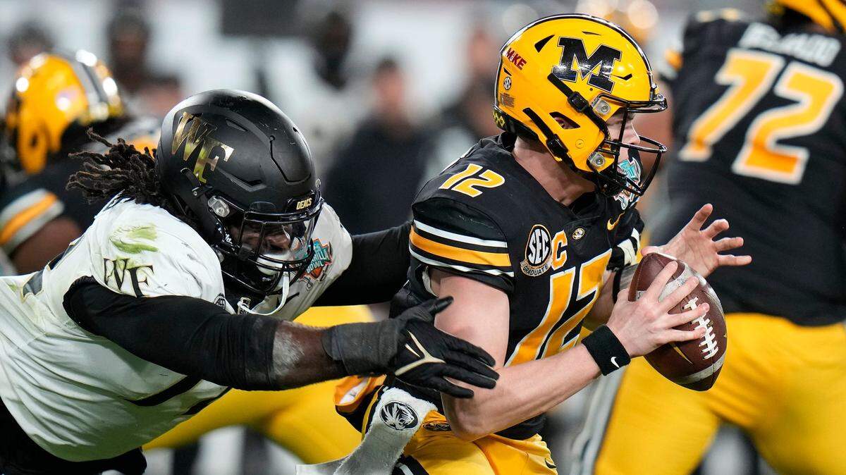 Missouri quarterback Brady Cook (right) slips free of Wake Forest defensive lineman Tyler Williams during Friday night’s Gasparilla Bowl game in Tampa, Fla.