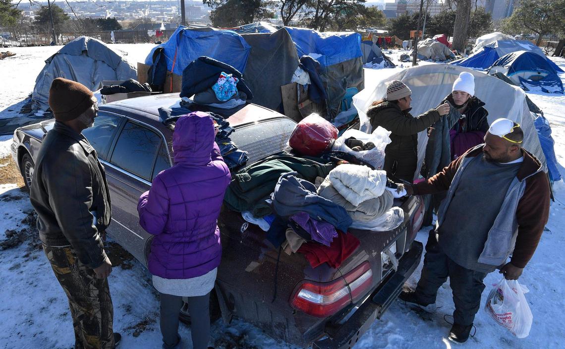 As winter settles in and temperatures drop dramatically, survival for the homeless becomes more difficult. On Monday afternoon at a well established camp on the northeast side of downtown, two volunteers, known as Jimmy and Judy, left, stopped by with some winter supplies for the residents there. The pair stop by the camp at least once a week with donations.