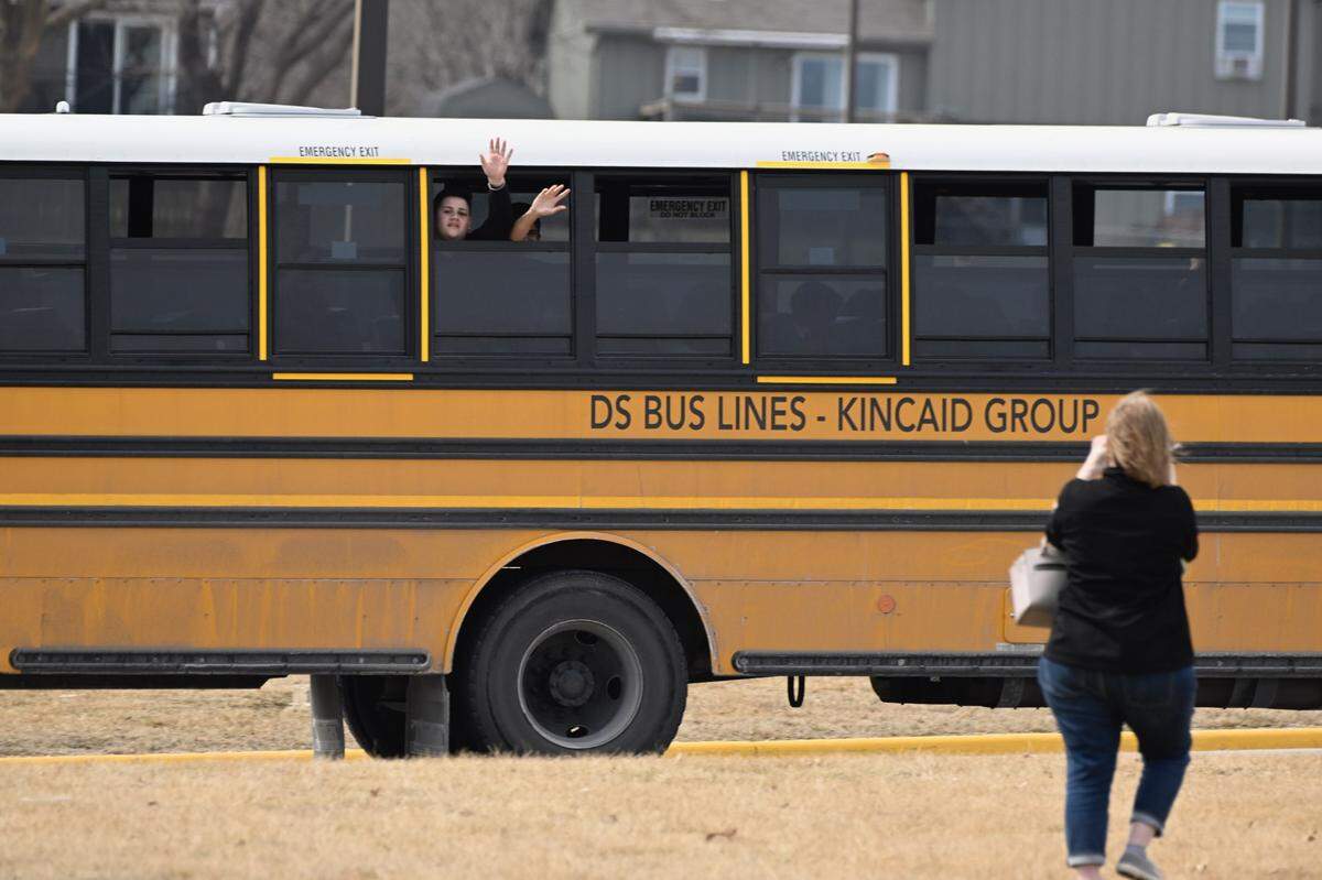Olathe East High School students wave to their parents Friday at the reunification site at Pioneer Trail Middle School where they were transported after a shooting at the high school.